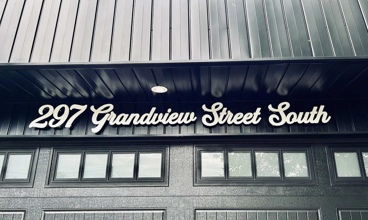 297 Grandview Street South in white script on dark siding at night